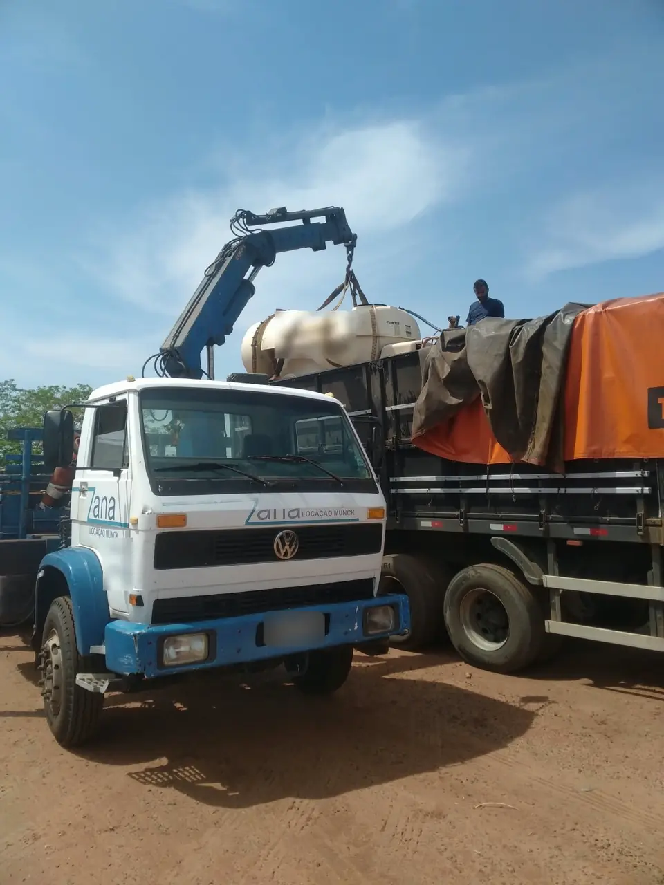 Caminhão munck da Zana carregando implemento agrícola em outro caminhão