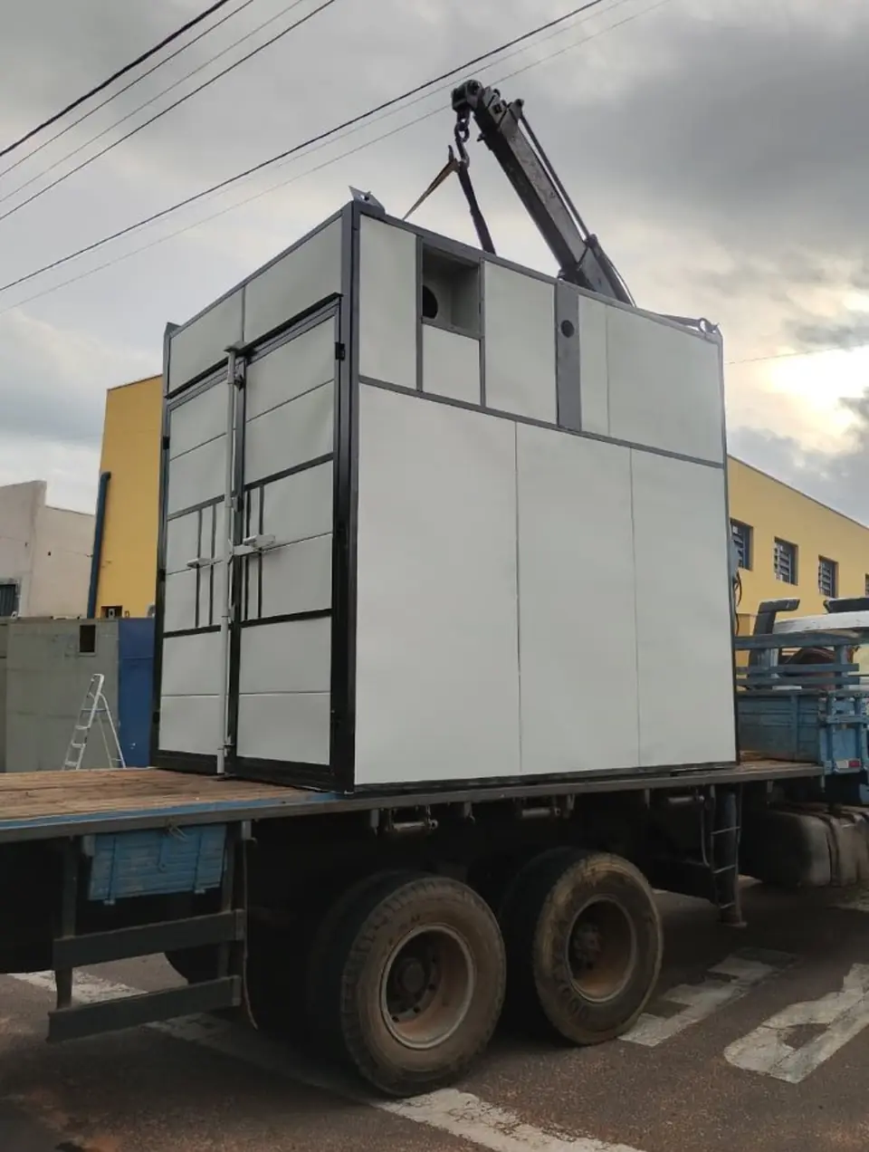Cabine metálica içada e transportada na carroceria do caminhão munck da Zana