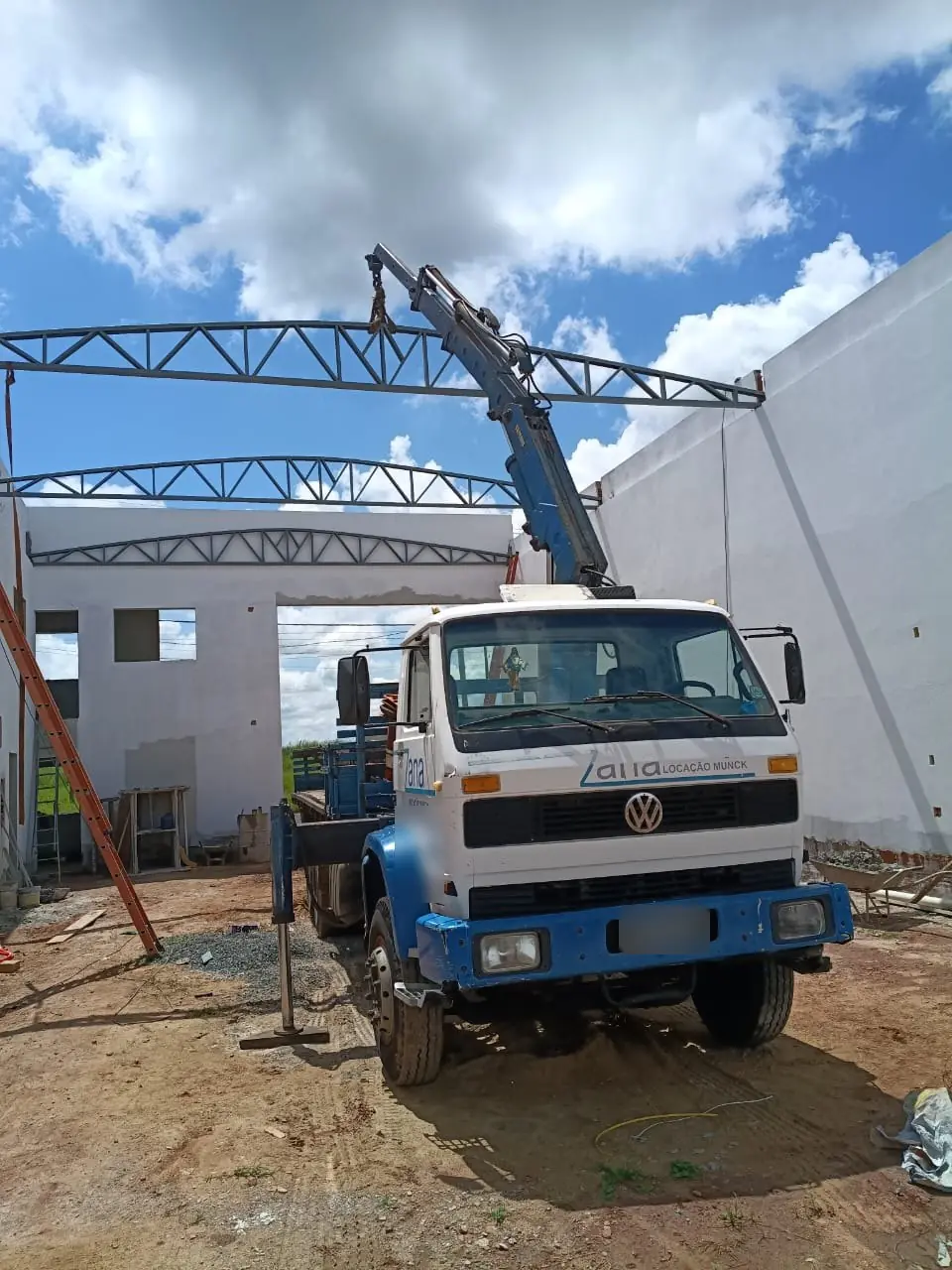 Caminhão munck da Zana içando treliça metálica de cobertura em obra em Catanduva