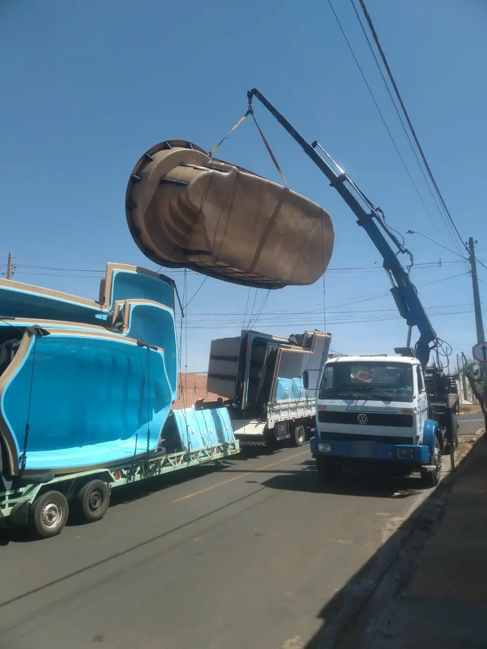 Caminhão munck da Zana descarregando piscina de fibra de uma carreta na região de Catanduva
